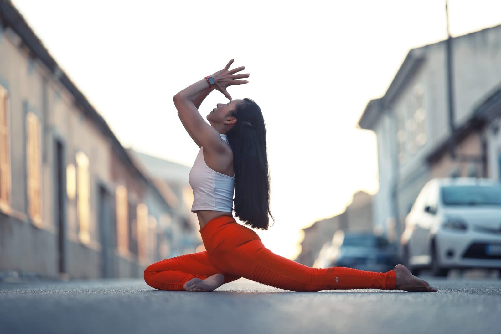 Wipa in a deep lunge with an extended reverse-warrior stretch on a city street